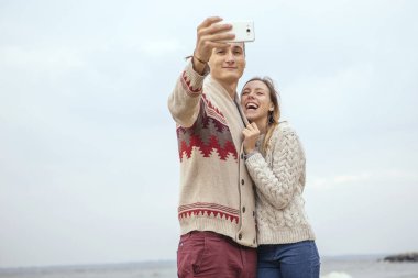 Mutlu düşünceli çift ayakta deniz huggin yakınındaki bir rock Beach