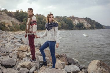 Mutlu düşünceli çift ayakta deniz huggin yakınındaki bir rock Beach