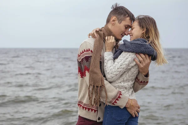 Feliz pareja pensativa de pie en una playa de roca cerca de abrazo al mar — Foto de Stock