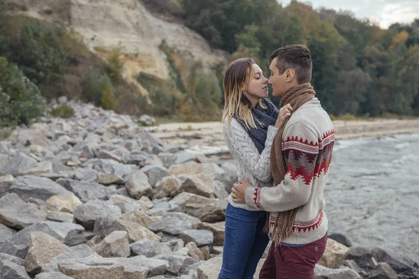 Feliz casal pensativo em pé em uma praia de rocha perto do abraço do mar — Fotografia de Stock