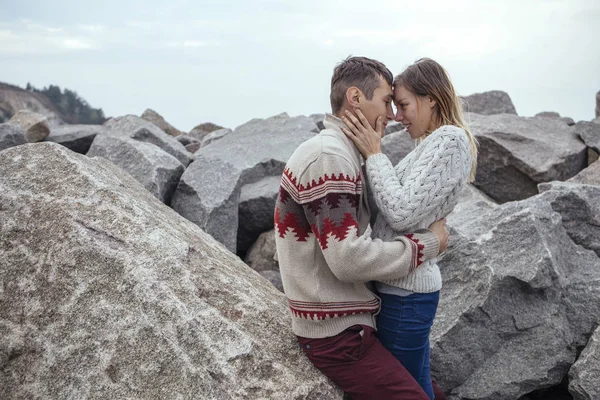 Feliz casal pensativo sentado em uma praia de rocha perto do mar abraçando — Fotografia de Stock