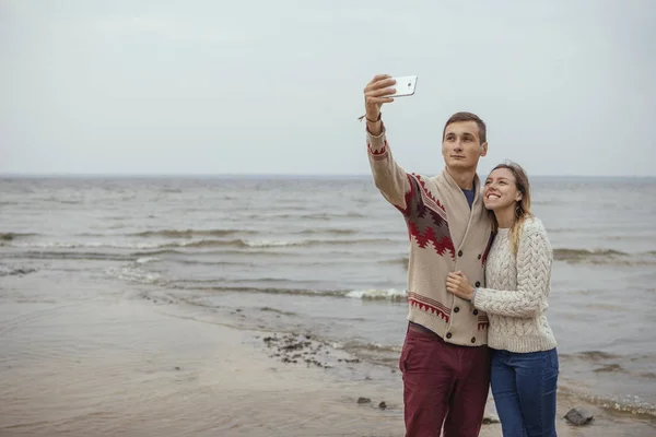 Felice coppia premurosa in piedi su una spiaggia rocciosa vicino abbraccio mare — Foto Stock
