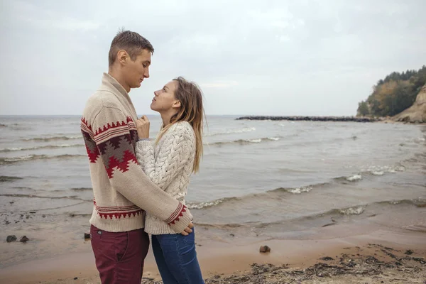 Feliz casal pensativo em pé em uma praia de rocha perto do abraço do mar — Fotografia de Stock