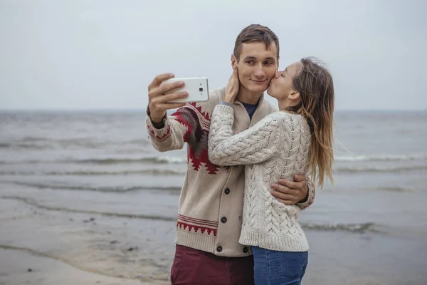 Glada omtänksamma par stående på en rock strand nära havet huggin — Stockfoto