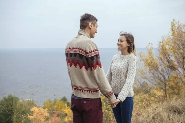 Feliz pareja pensativa de pie en un acantilado cerca del mar abrazando cada uno — Foto de Stock