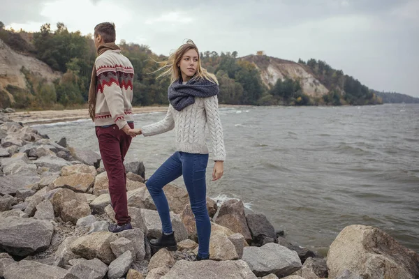 Happy thoughtful couple standing on a rock beach near sea huggin — Stock Photo, Image