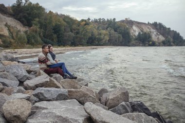 Mutlu düşünceli çift ayakta deniz huggin yakınındaki bir rock Beach