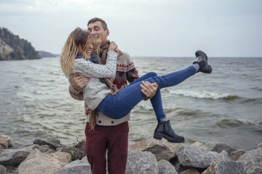 Mutlu düşünceli çift ayakta deniz huggin yakınındaki bir rock Beach