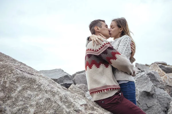 Feliz casal pensativo sentado em uma praia de rocha perto do mar abraçando — Fotografia de Stock