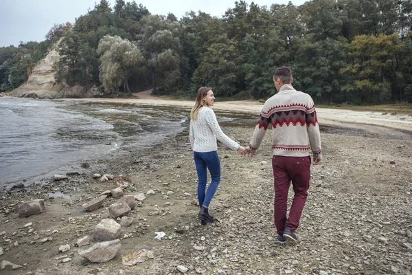 Felice coppia premurosa in piedi su una spiaggia rocciosa vicino abbraccio mare — Foto Stock