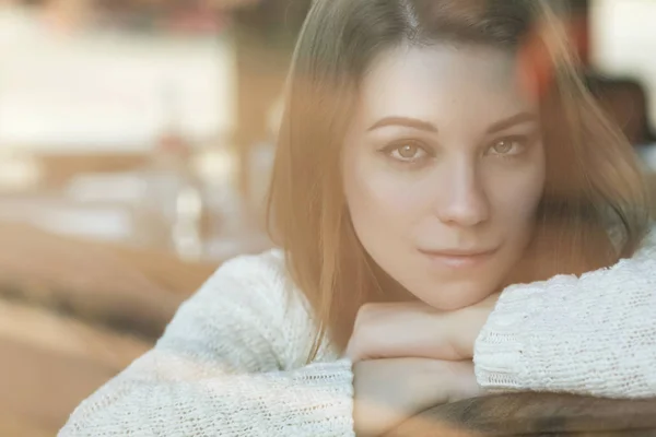 Beautiful young teenage caucasian woman in sweater sitting at th — Stock Photo, Image