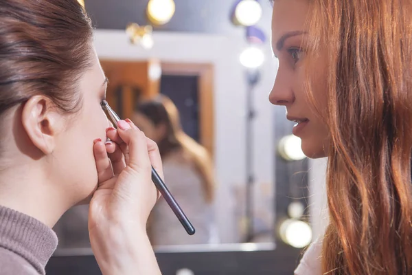 Profesional maquillaje artista aplicar rímel a un joven caucásico w —  Fotos de Stock