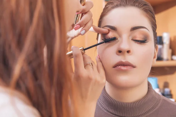 Professional make up artist apply mascara to a young caucasian w — Stock Photo, Image