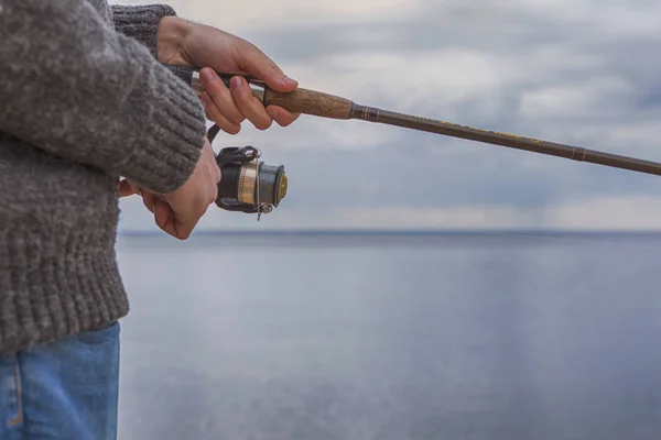 Молодий красивий жорстокий кавказький чоловік у повсякденному вбранні риболовлі на — стокове фото