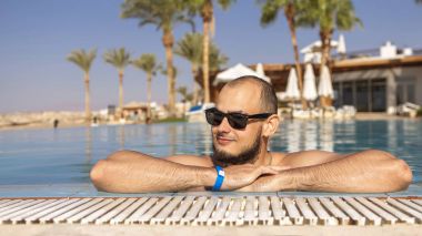 Seksi yakışıklı beyaz adam üzerinde açık yüzme havuzunda oturuyor 