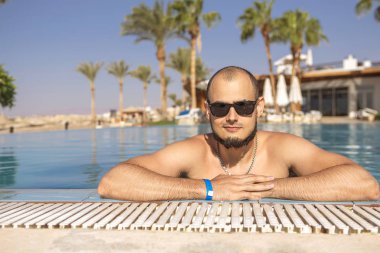 Seksi yakışıklı beyaz adam üzerinde açık yüzme havuzunda oturuyor 