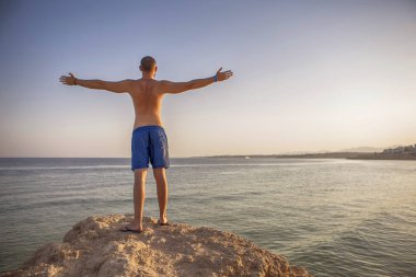 Seksi ince uygun esmer adam Mavi mayo keyfini çıkarın tatil, stan