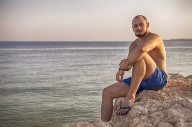 Seksi ince uygun esmer adam Mavi mayo keyfini çıkarın tatil, stan