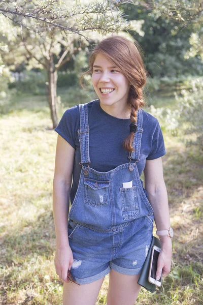 Süße glückliche Kaukasierin mit langen roten Haaren und Jeans im Park — Stockfoto