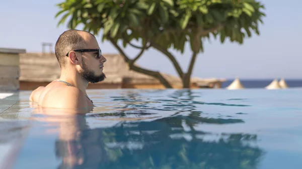 Sexy knappe blanke man zit in zwembad buiten op — Stockfoto