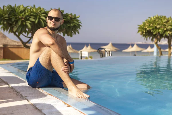 Sexy knappe blanke man zit in zwembad buiten op — Stockfoto