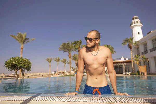 Seksi yakışıklı beyaz adam üzerinde açık yüzme havuzunda oturuyor 