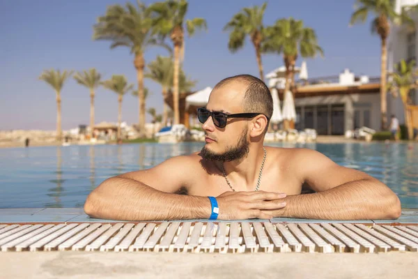 Seksi yakışıklı beyaz adam üzerinde açık yüzme havuzunda oturuyor 