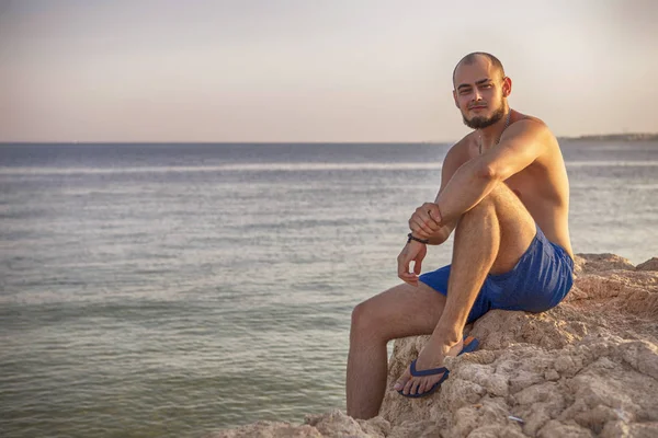 Seksi ince uygun esmer adam Mavi mayo keyfini çıkarın tatil, stan