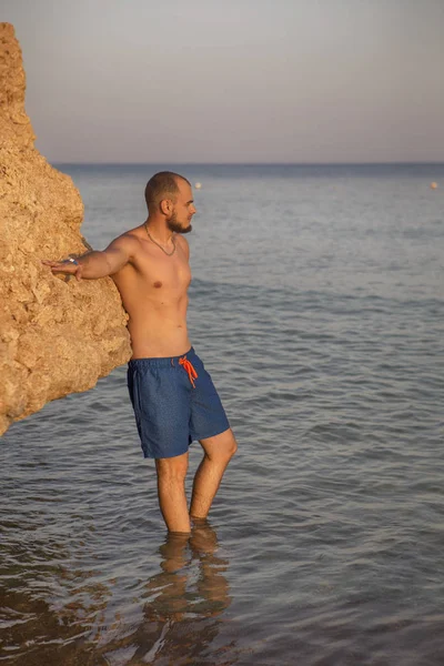 Seksi ince uygun esmer adam Mavi mayo keyfini çıkarın tatil, stan