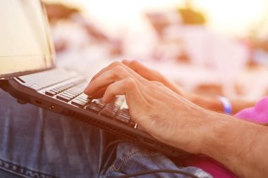 Bir dizüstü bilgisayarda uzaktan çalışma, yazarak, bir tropikal üzerinde oturan adam 