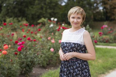 Yaşlı kadın onu serbest zaman Park'ta rahatlatıcı yürüyüş üzerinde yaşlı. Neşeyle gülümseyerek. Güneşli bir gün. Kopya alanı