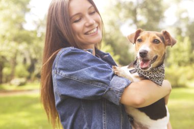 Sevimli güzel ince beyaz esmer kadın gündelik kıyafeti (etek, tişört ve kot ceket) yaz günü çok güzel onunla parkta bir yürüyüş jack russell köpek. Onlar dolu sevinç, gülümseyen ve eğlenin