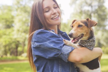 Sevimli güzel ince beyaz esmer kadın gündelik kıyafeti (etek, tişört ve kot ceket) yaz günü çok güzel onunla parkta bir yürüyüş jack russell köpek. Onlar dolu sevinç, gülümseyen ve eğlenin