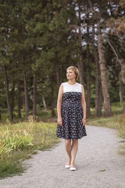 Elder aged woman on her free time walking relaxing in park. Smiling cheerfully. Sunny day. Copy space