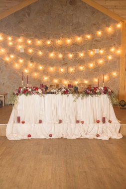 Şarap rengi mumlar, Kaplamalar ve ışık çelenk ve çiçek çevrili masa örtüsü ile düğün tablolar kümesi. İç. Kopya alanı