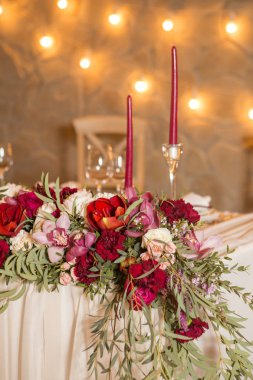 Şarap rengi mumlar ışık çelenk ve çiçek çevrili bir düğün tablo kümesi. İç. Kopya alanı