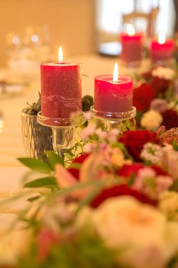 Şarap rengi mum ışıklarıyla çevrili bir düğün tablo kümesi