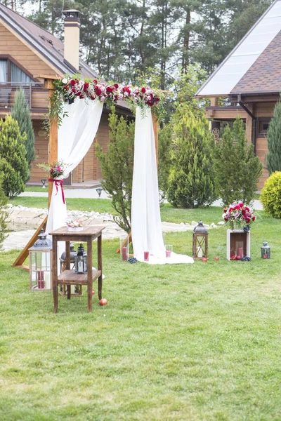 葡萄酒颜色的花朵在婚礼拱门上 有薄纱面料和木制装饰品 复制空间 — 图库照片