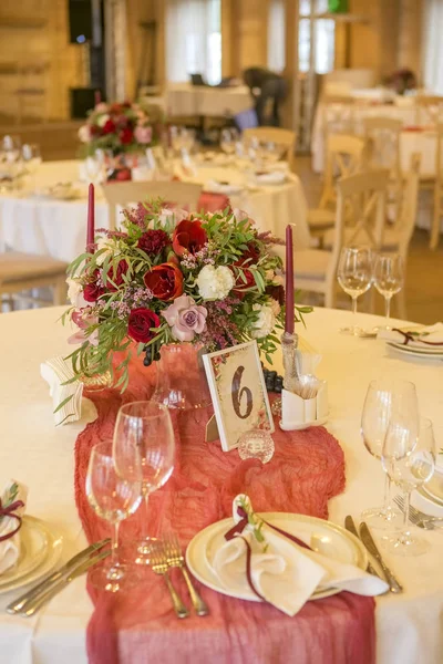Set of wine flowers on a wedding table surrounded by plates, tablecloths and candles. Interior. Copy space
