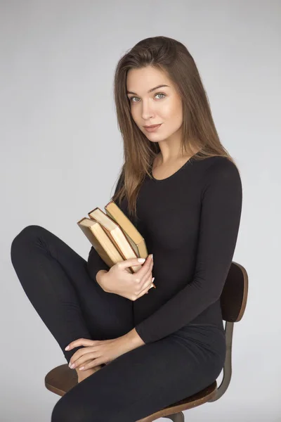 Ung vacker brunett kvinna sitter på en stol i neutrala cas — Stockfoto