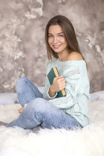 Jovem bela mulher caucasiana sentado em uma cama, livro de leitura . — Fotografia de Stock
