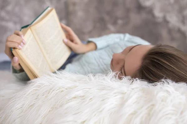 Kitap okuma bir yatak üzerinde oturan genç güzel beyaz kadın. — Stok fotoğraf