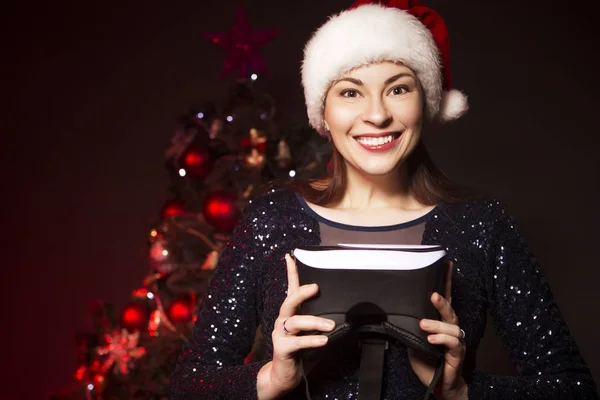 Nette Lächelnde Frau Mit Weihnachtsmütze Und Abendkleid Präsentiert Ihre Brille — Stockfoto