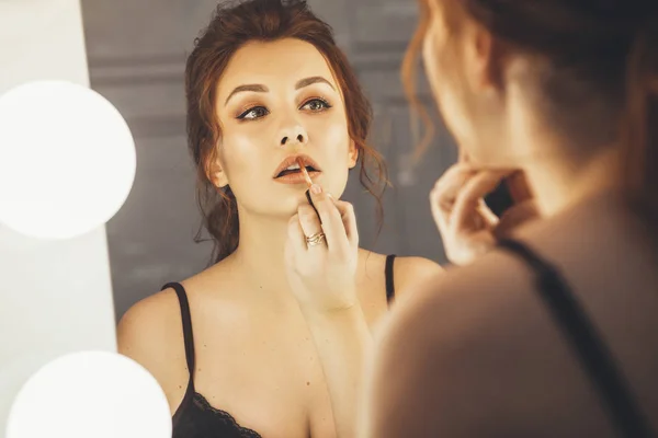 Brunett kvinna tillämpa make up (måla hennes läppar) för en kväll-d — Stockfoto
