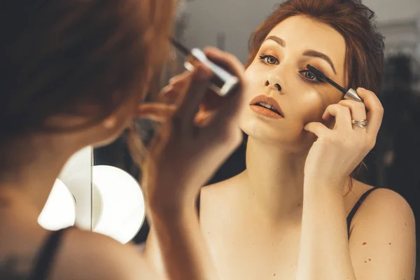Mujer morena aplicando maquillaje (pintar sus pestañas) para un par —  Fotos de Stock