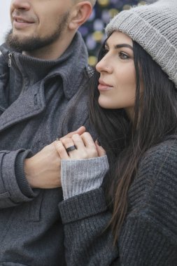 Muhteşem güzel beyaz bir kadın kış Avrupa kenti bir yolda bir adamla. Çift sıradan gri kıyafet ve birbirlerine sarılma giymek. Soğuk hava, bir arka plan üzerinde Noel ışıkları