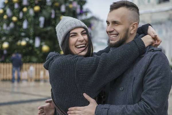 冬のヨーロッパの都市の散歩の男で豪華な美しい白人女性 カジュアルなグレーの服とお互いをハグを着用するカップル 背景にクリスマス ライト — ストック写真