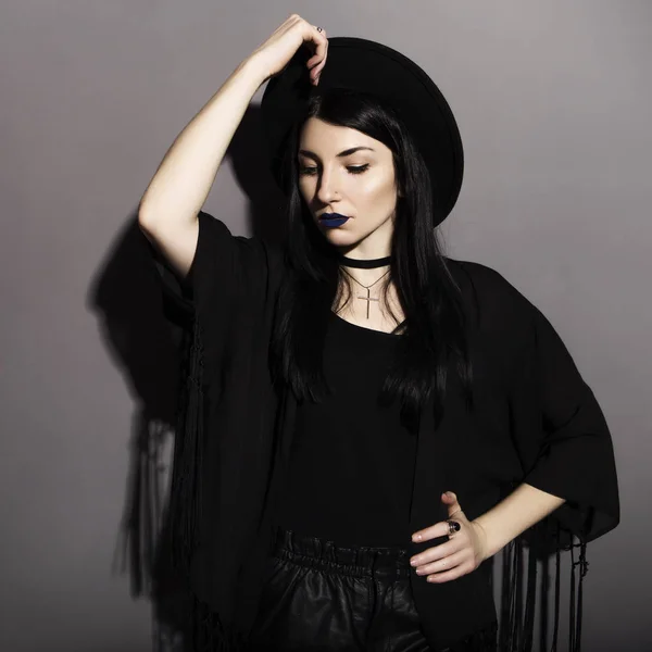 Gotische Kaukasische vrouw in donkere kleding op een grijze neutrale pagina — Stockfoto