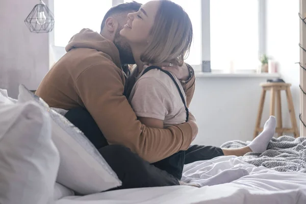 Elegante pareja hipster de hombre y mujer sentados en la cama en su — Foto de Stock