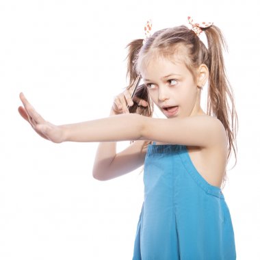 Beyaz izole zemin üzerinde mavi elbiseli Genç yedi yaşında esmer kız. Öfkeli duygular yüzünde. Mutsuz telefonda konuşurken bir şey hakkında o